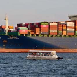 a large ship infront of the boat of Southport Water Tours