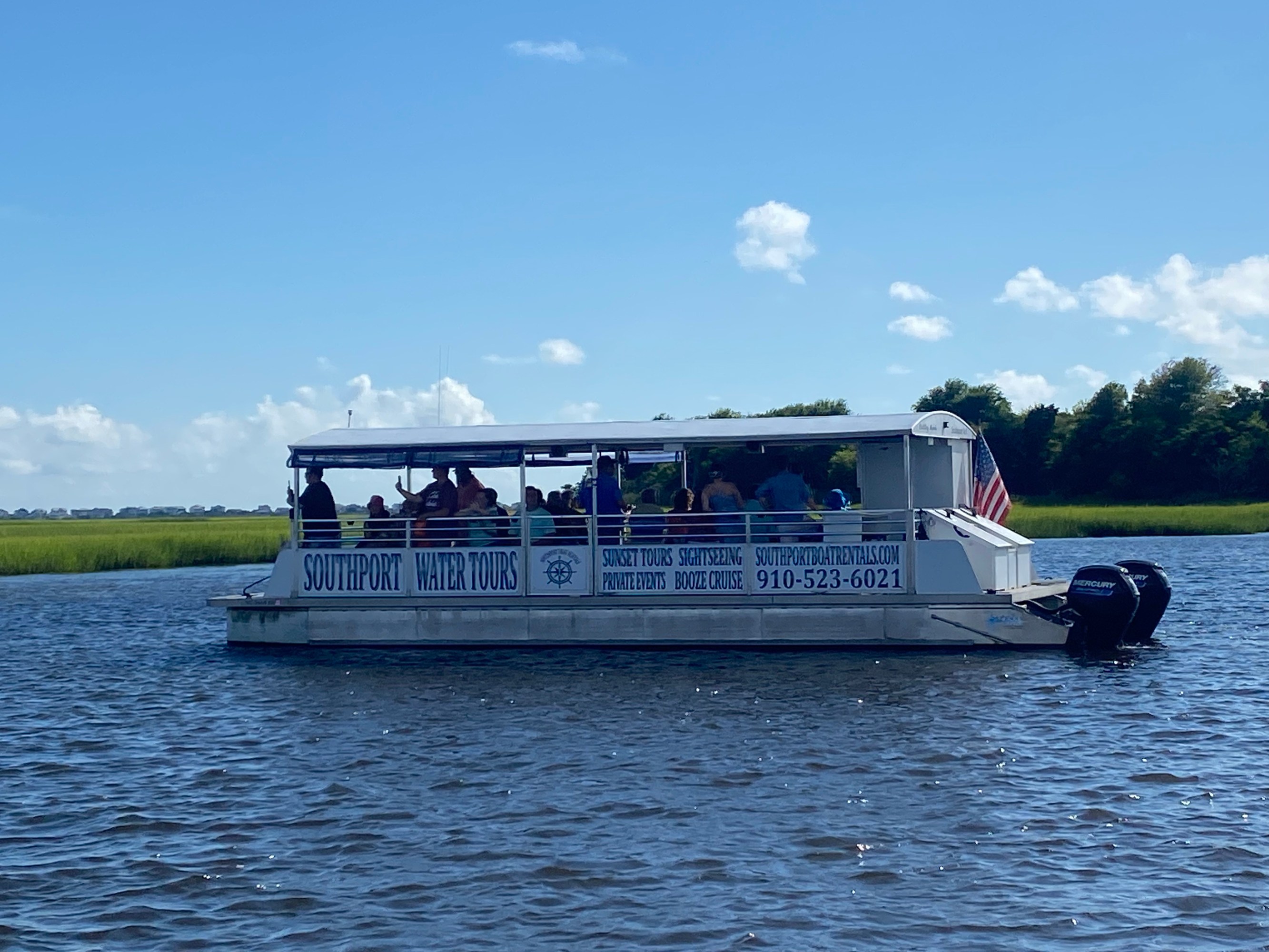 People on a boat labeled 'Southport Water Tours' cruising on a sunny day.