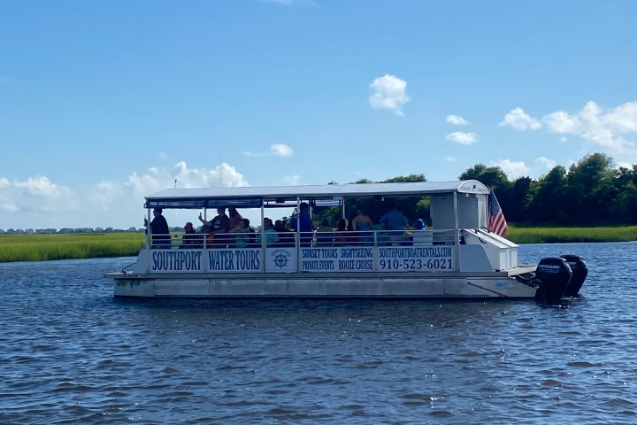 People on a boat labeled 'Southport Water Tours' cruising on a sunny day.